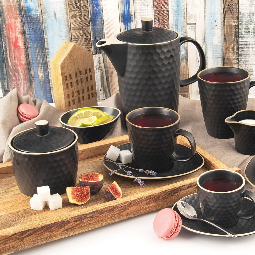 Una mesa con juego de té negro, higos, cubos de azúcar, macarrones y rodajas de limón en una bandeja de madera. Decoración de casa de madera.