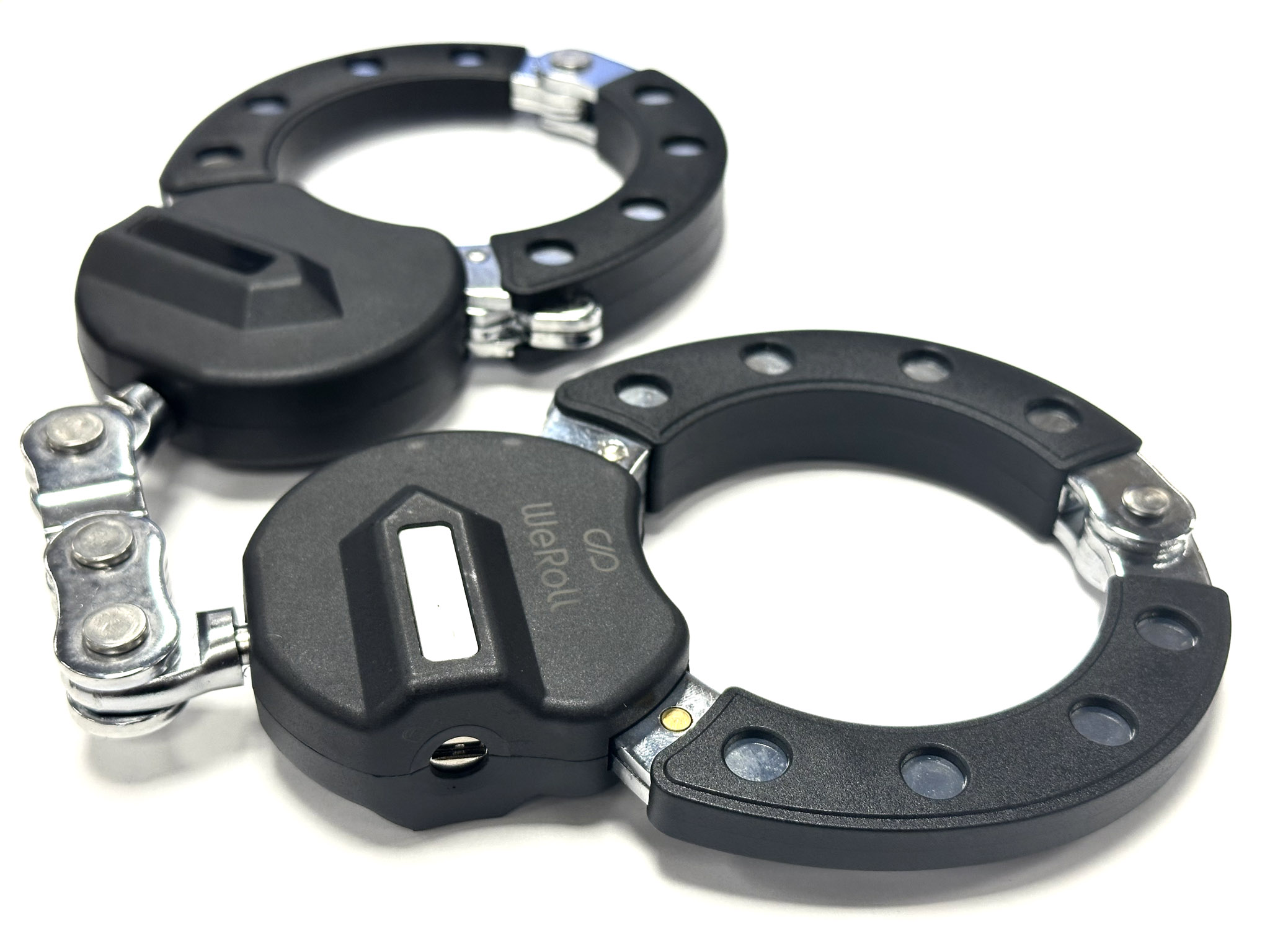 Zwei schwarze Handschellen auf weißem Untergrund. Die Handschellen sind geöffnet, mit einem rechteckigen schwarzen Mittelteil und einer silbernen Kette.