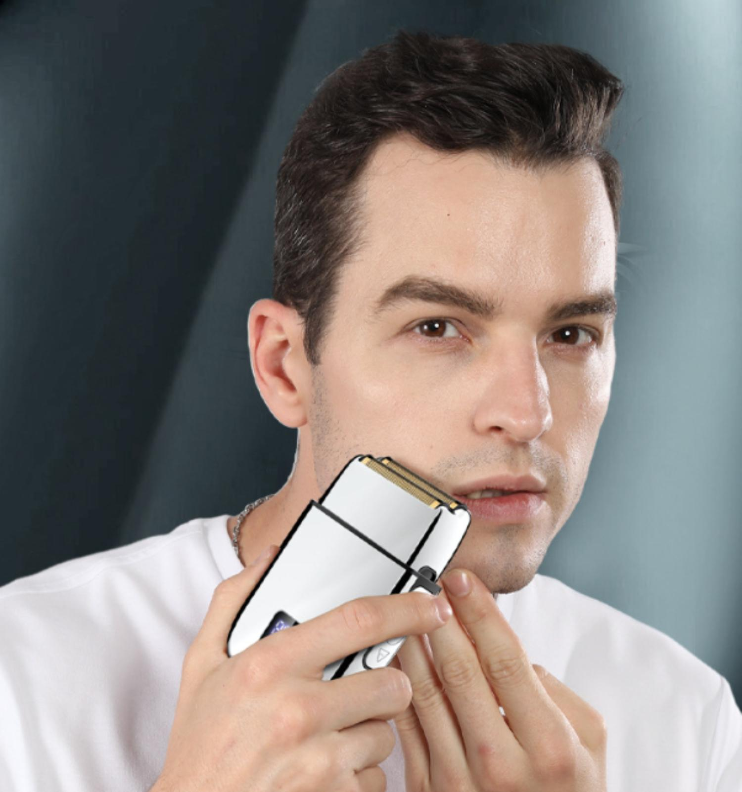 Ein Mann rasiert sich mit einem Elektrorasierer. Er trägt ein weißes Hemd, der Hintergrund ist grau und blau.