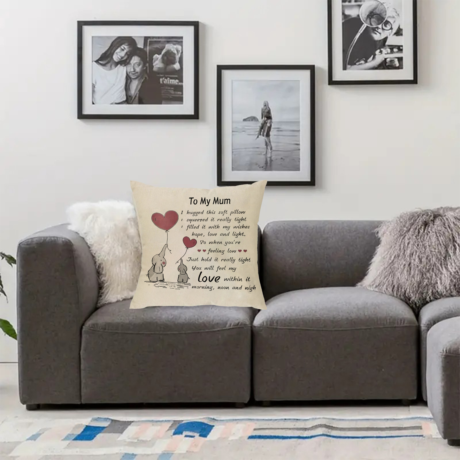 Graues Sofa mit Kissen mit Zeichnung von zwei Elefanten, die Herzballons halten. Wandkunst ist oben.