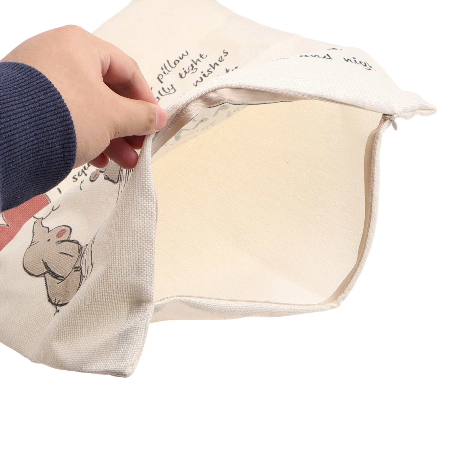 Eine Hand öffnet einen Kissenbezug. Der Kissenbezug ist beige mit Reißverschluss und Cartoon-Tierdrucken.