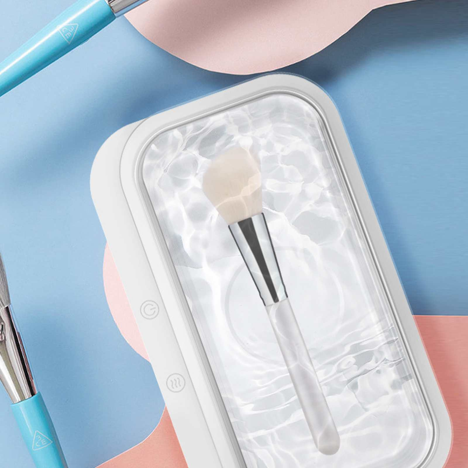 Make-up-Pinsel in einem transparenten Behälter mit Wasser-Effekt. Blauer und rosa Hintergrund. Ein weiterer Pinsel links.