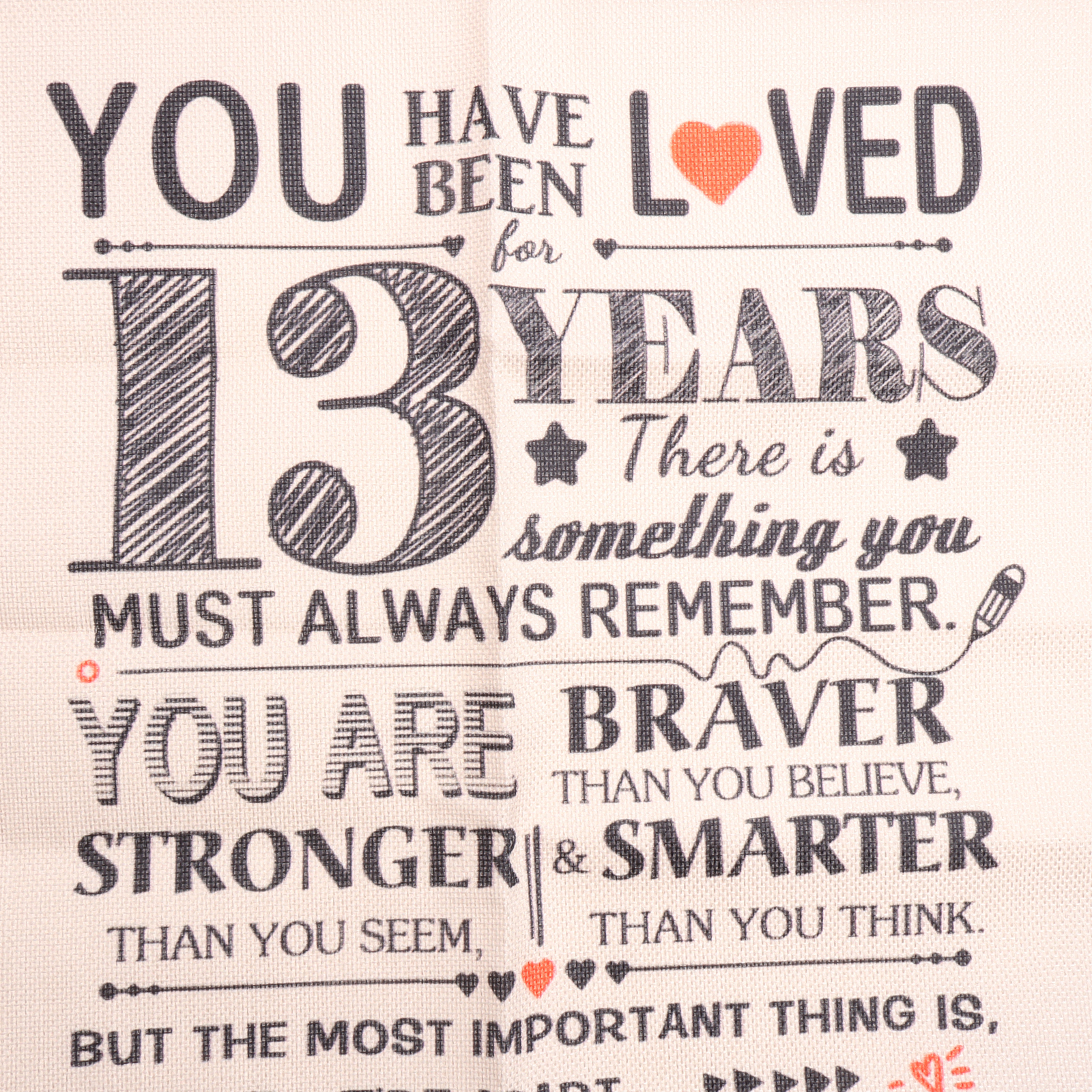 Weißer Stoff mit schwarzem Text: 'YOU HAVE BEEN LOVED for 13 YEARS...'. Ein orangefarbenes Herz ist ebenfalls vorhanden.