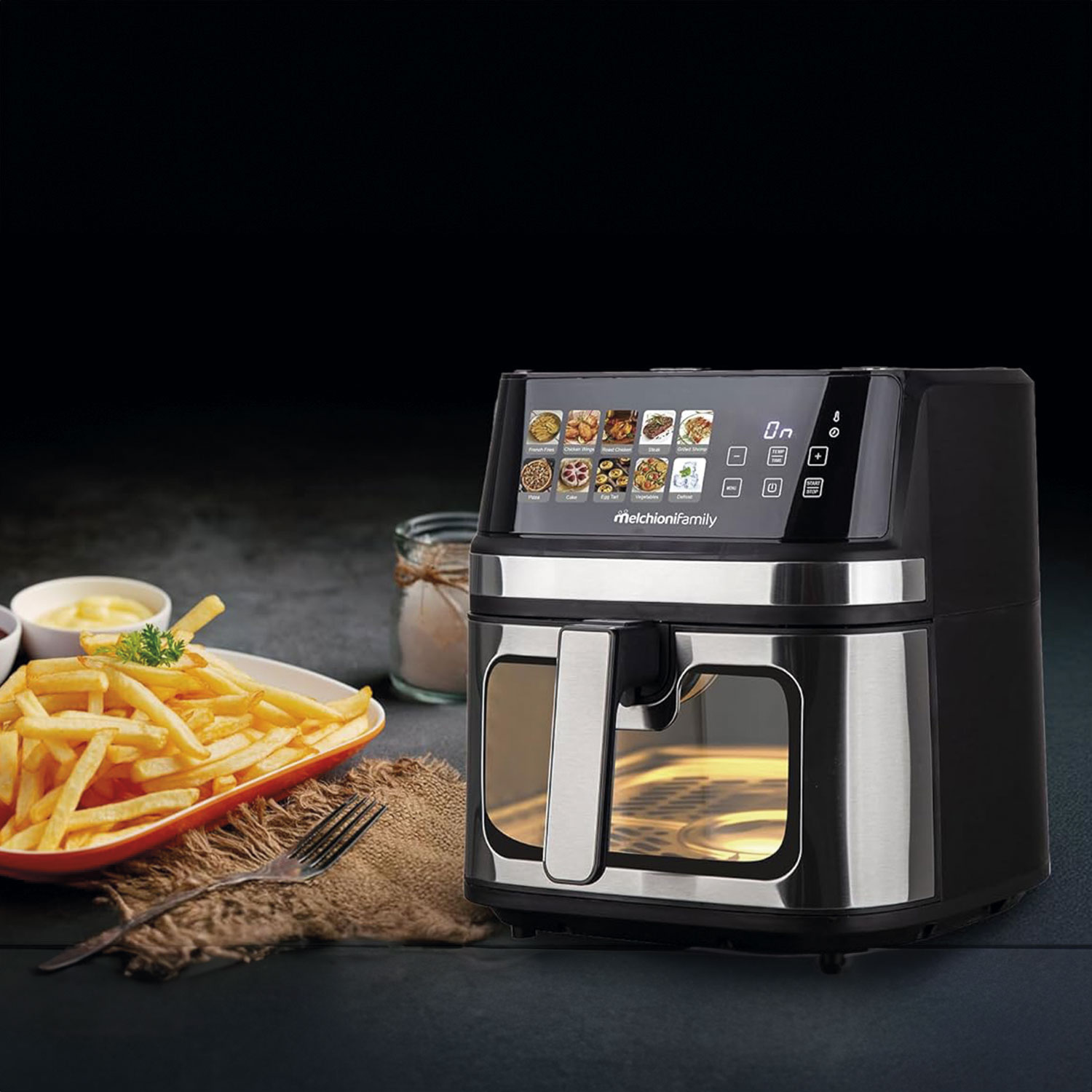 Una freidora de aire con pantalla digital está junto a papas fritas en un plato con salsas. El fondo es negro.
