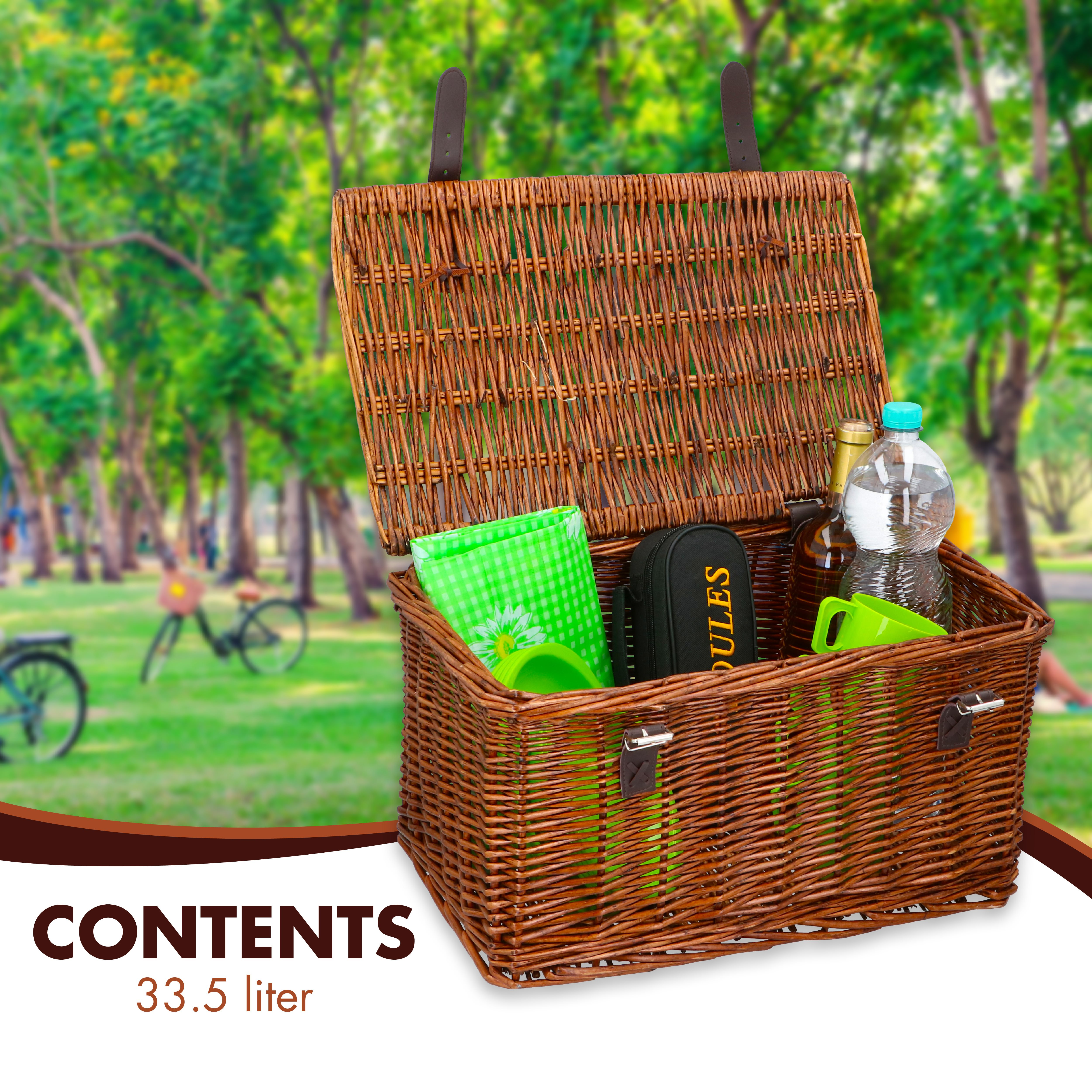 Open picknickmand van riet, gevuld met items zoals een fles, water, bekers en een groen geruite doek, in een park.