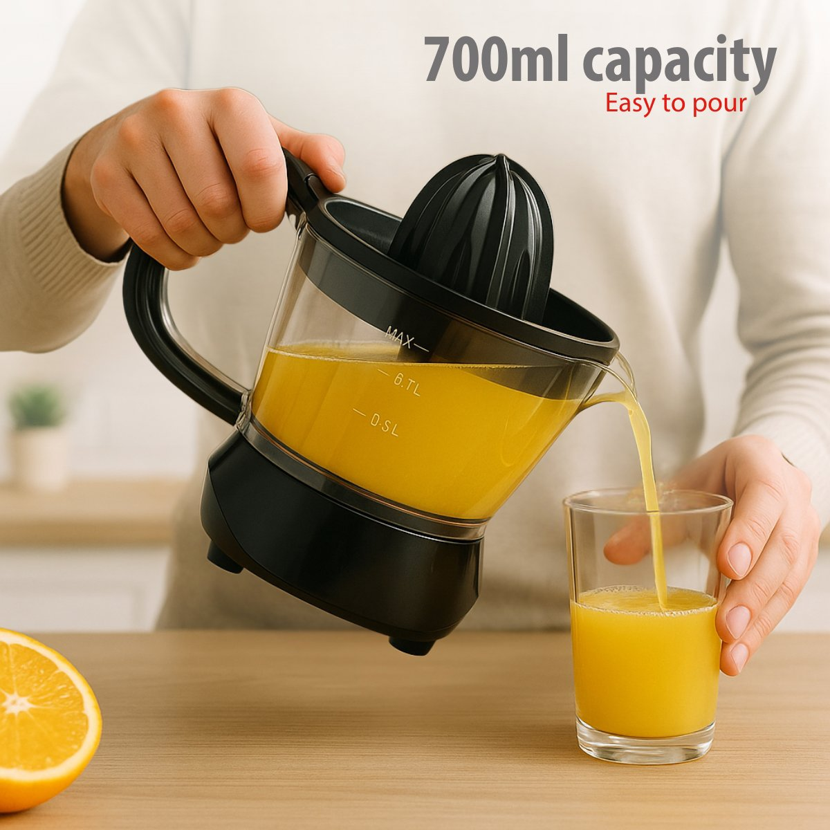 A person pours orange juice from a juicer into a glass. Half an orange is on the table. The juicer has a 700ml capacity.