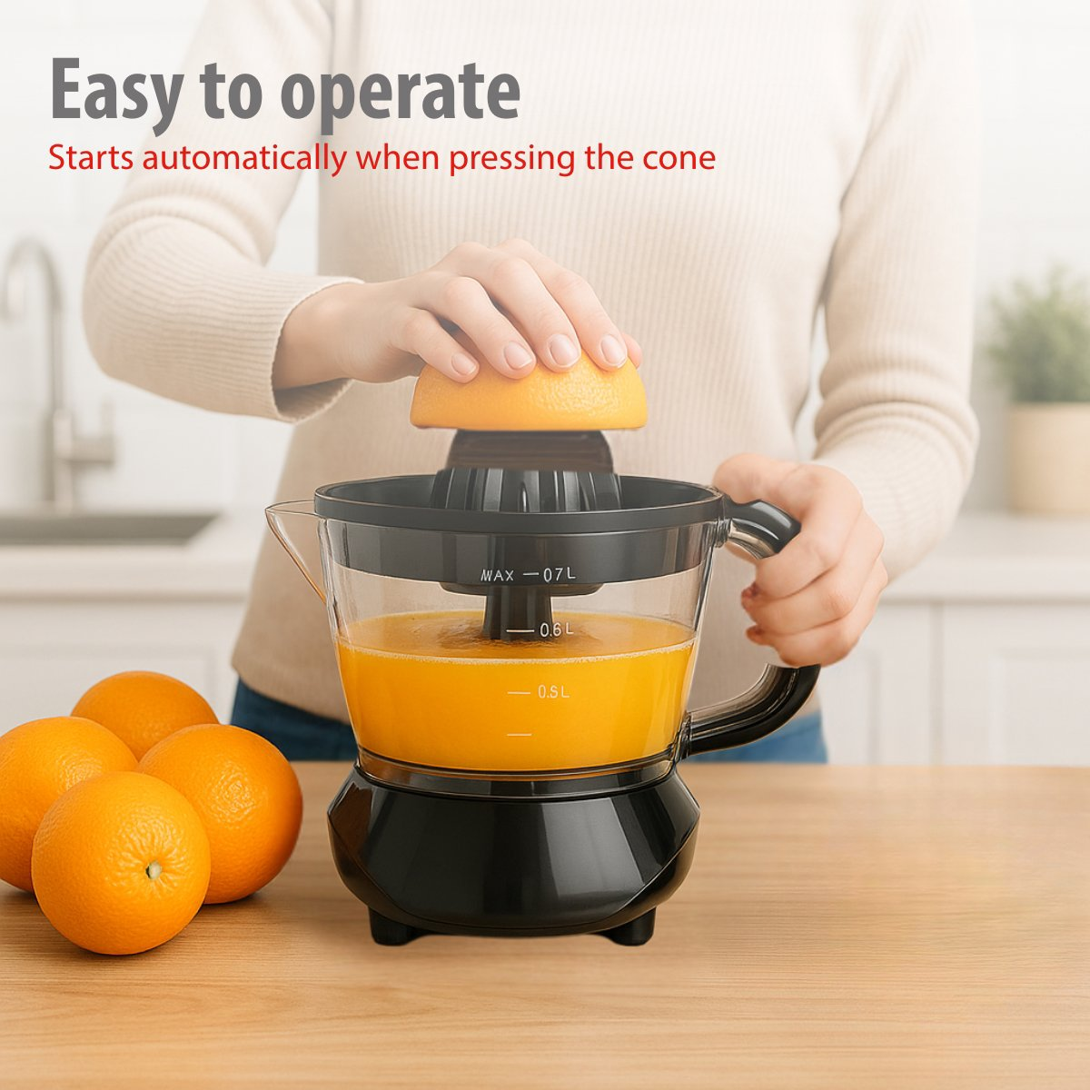 A person squeezing an orange with a juicer. Oranges are on the table. The juicer is black and clear, full of orange juice.