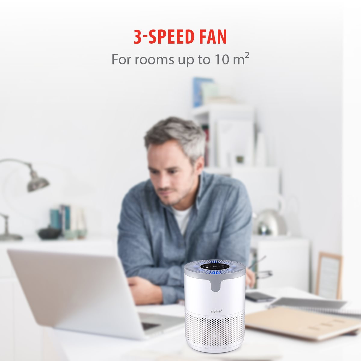 Ein Mann sitzt an einem Schreibtisch mit einem Laptop. Im Vordergrund steht ein weißer Luftreiniger. Text: 3-SPEED FAN.