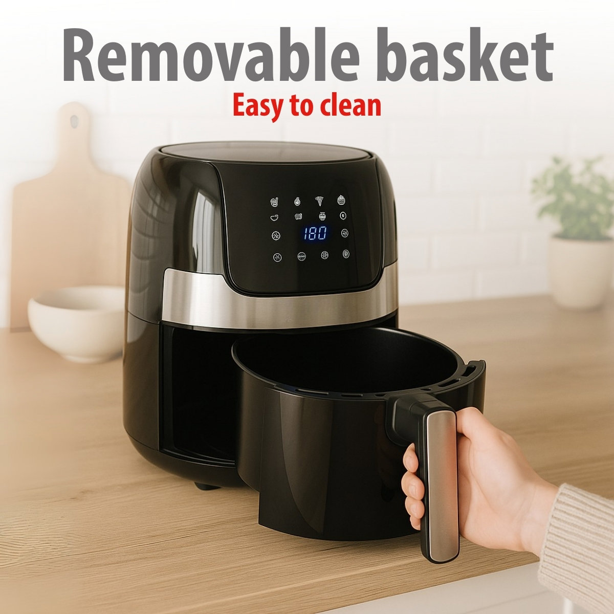 Een zwarte airfryer met de mand verwijderd, vastgehouden door een hand. De tekst 'Verwijderbare mand' en 'Gemakkelijk schoon te maken' staan erboven.