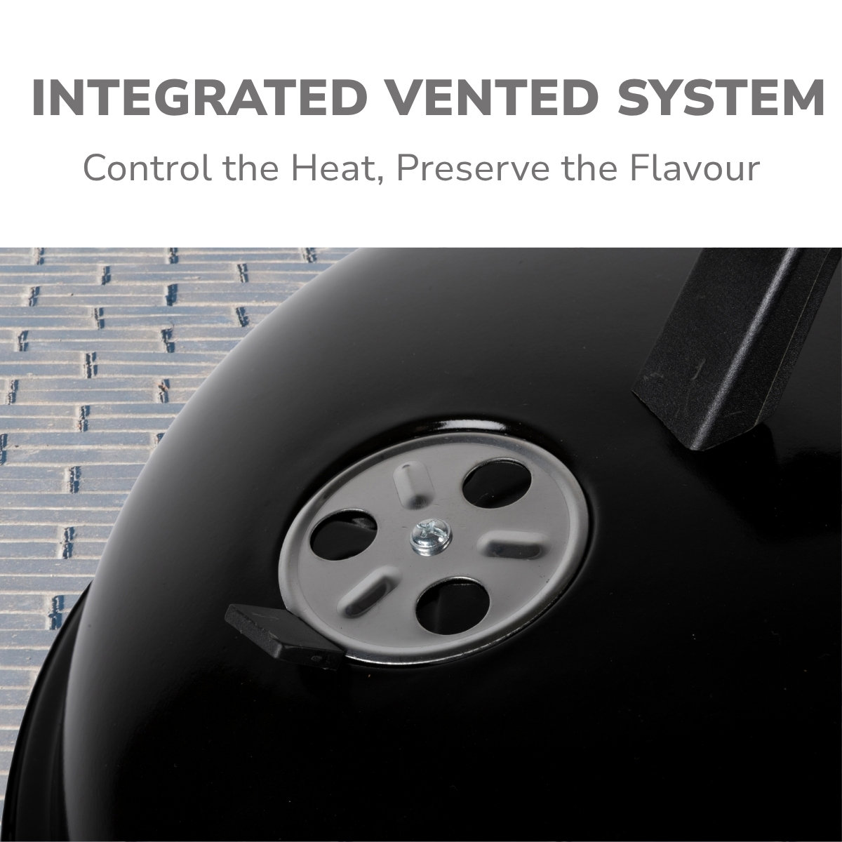 Close-up van een zwarte grill met een ventilatiesysteem. De ventilatieopening is zilverkleurig en heeft meerdere gaten. De grill heeft een handvat.