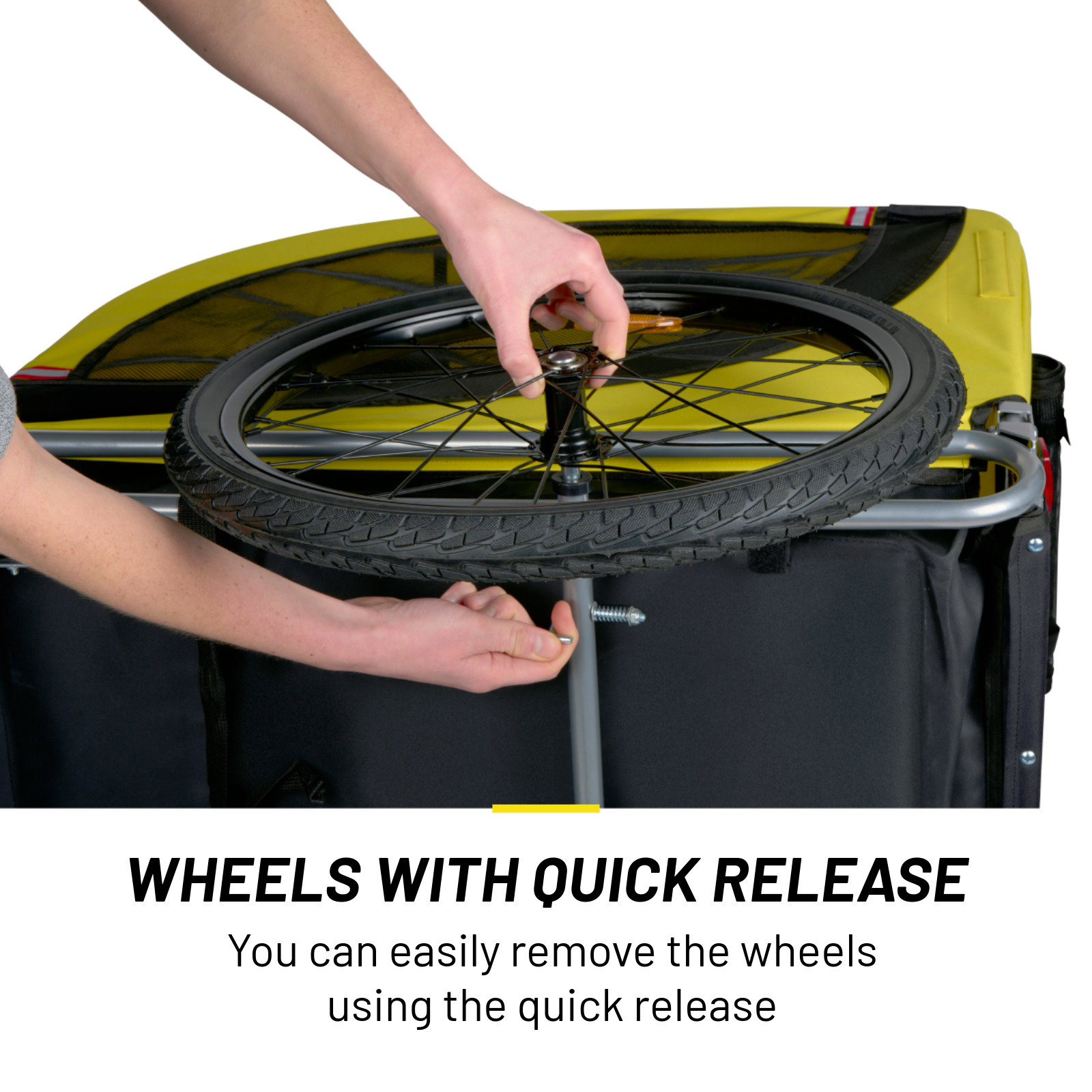 A person's hands are assembling a black tire wheel to a yellow and black trailer. The wheel has a quick release function.