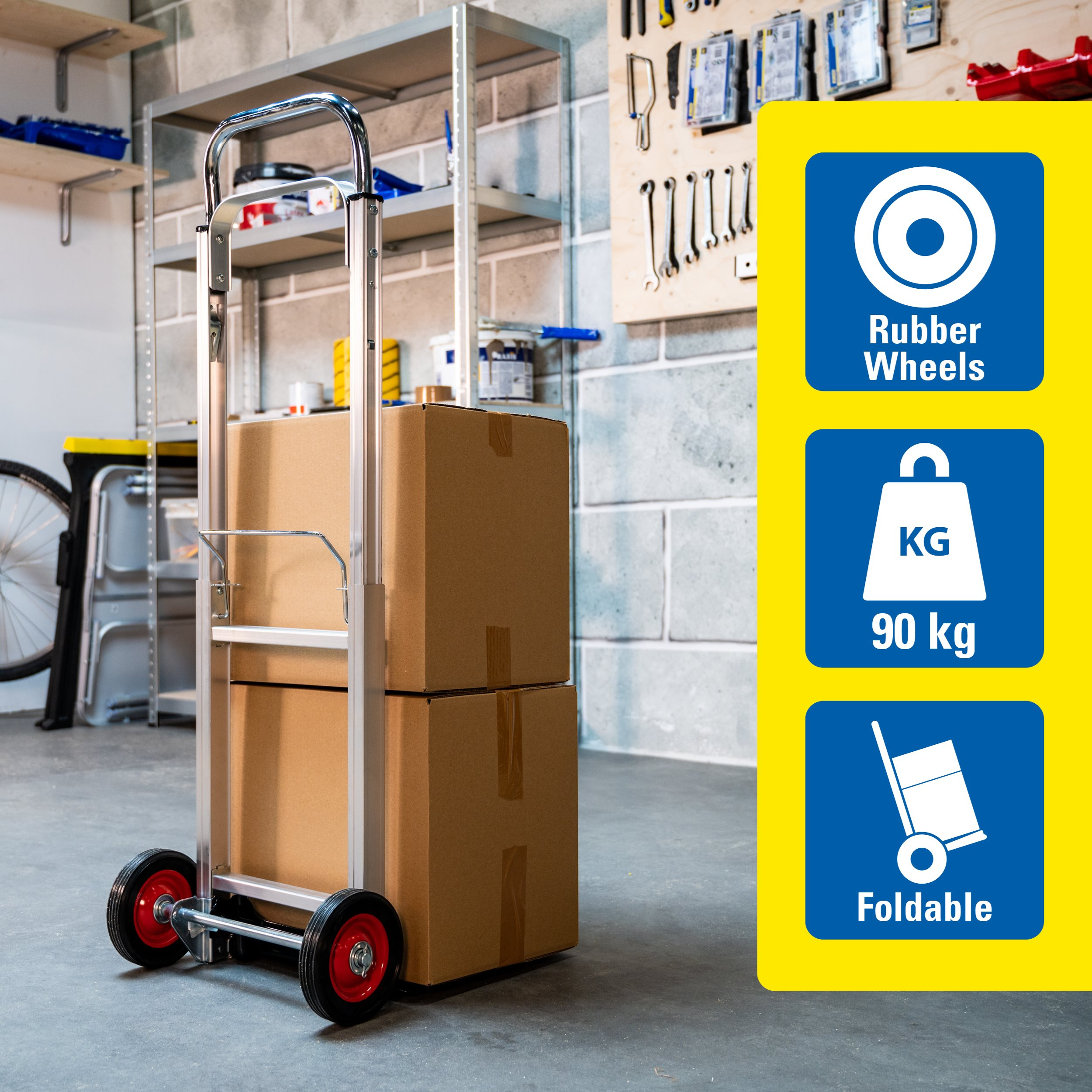 A hand truck with two cardboard boxes. It has red wheels and is foldable. The sign indicates rubber wheels, 90 kg capacity.
