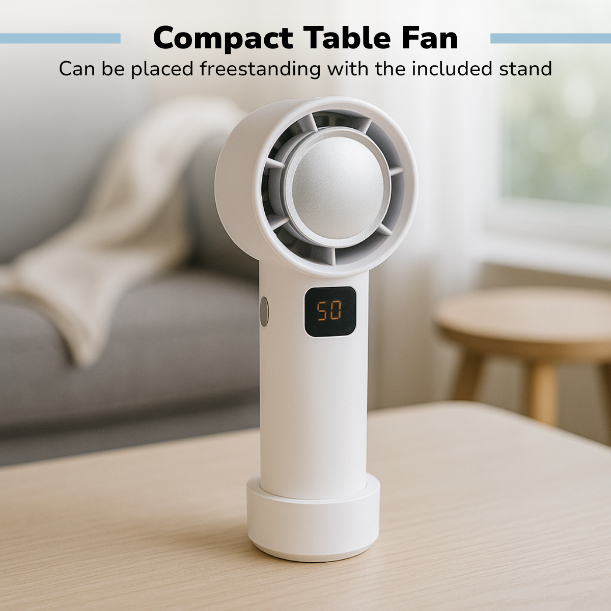 Un ventilateur de table blanc avec un affichage numérique indiquant '50' est posé sur une table en bois. Un canapé et un tabouret sont en arrière-plan.