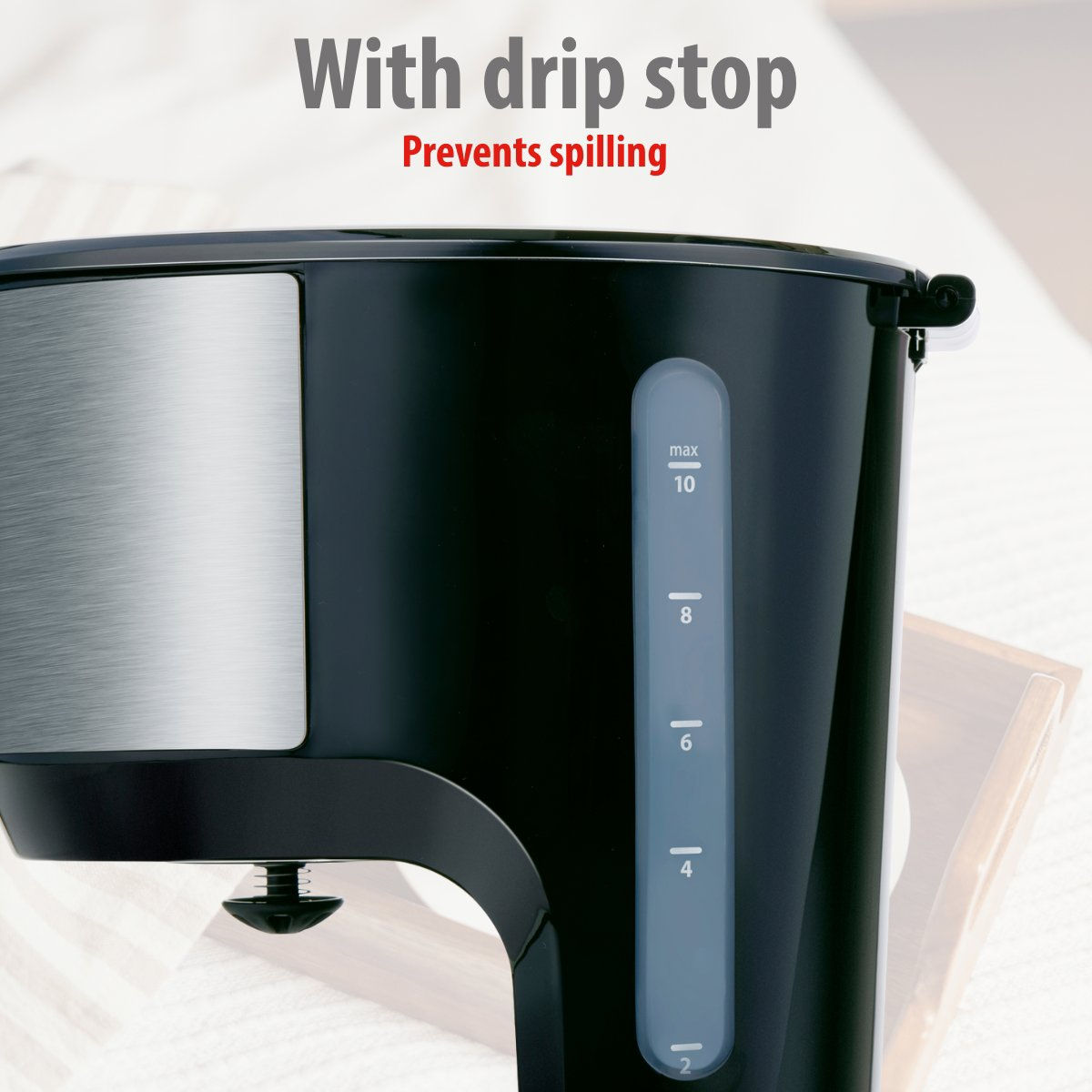 Close-up of a black coffee maker with a water level indicator. Text at the top reads 'With drip stop' and 'Prevents spilling'.