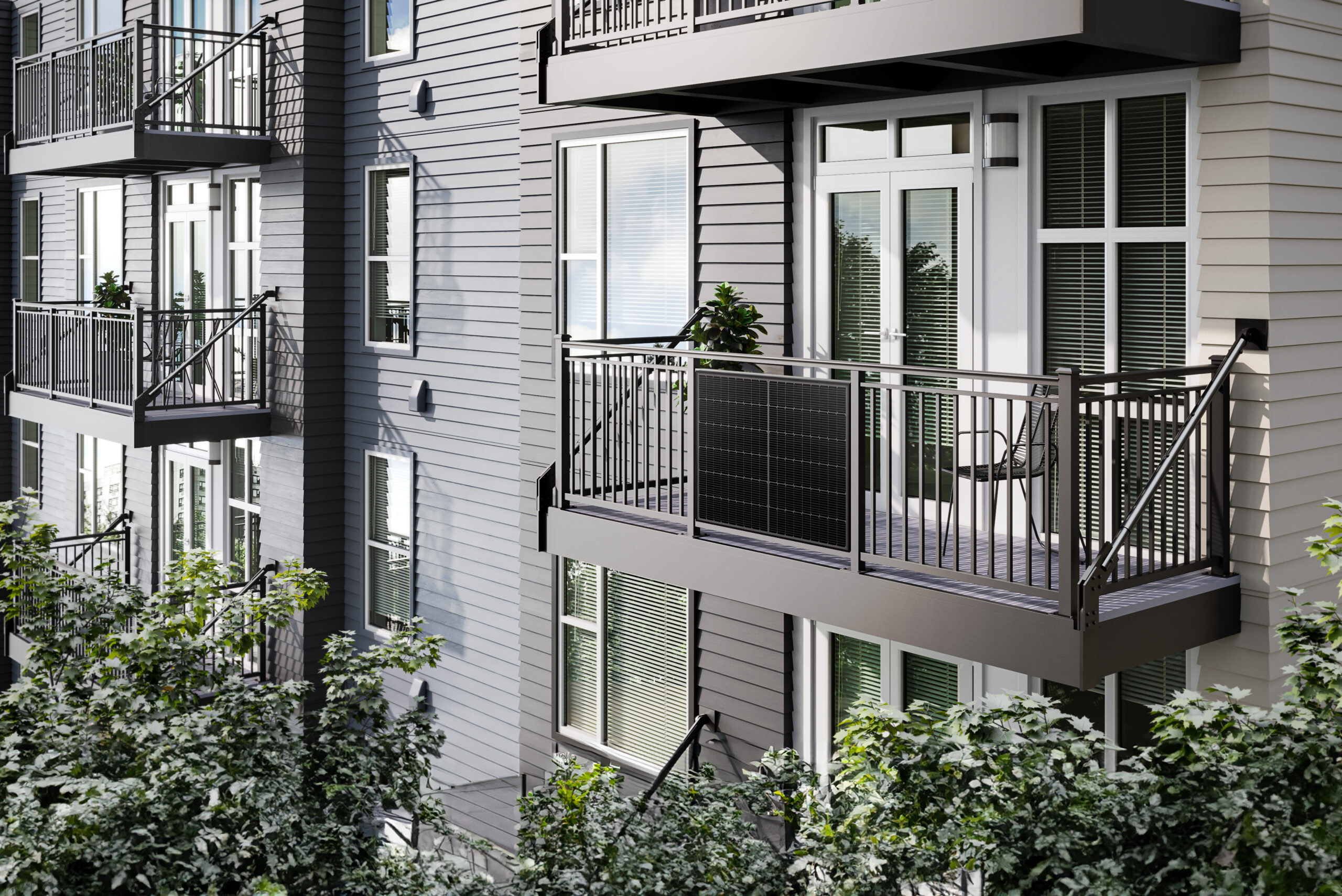 Edificio de apartamentos con balcones. Los balcones tienen barandillas negras, sillas y plantas. Las persianas son visibles a través de las ventanas.