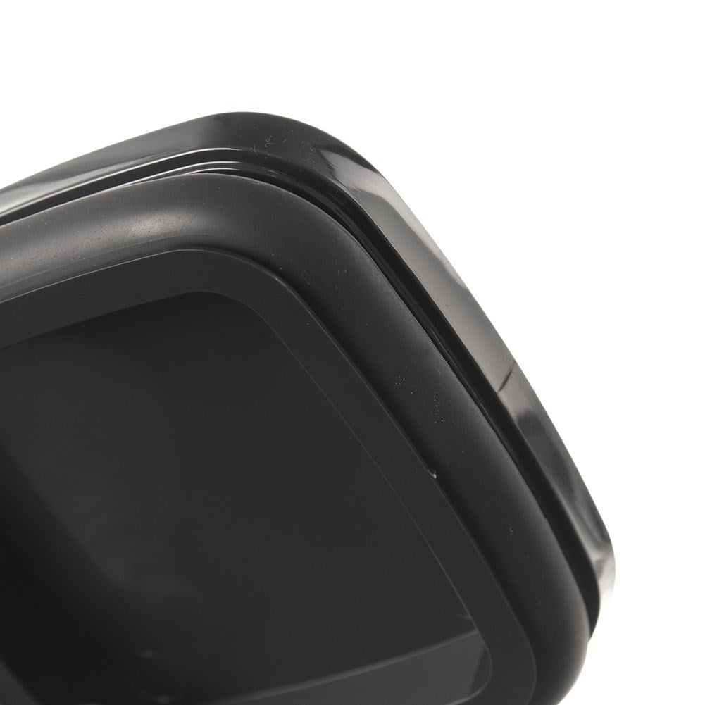 Primer plano de un recipiente negro de forma cuadrada. Se ve el borde de la tapa, con esquinas redondeadas y superficie brillante. Fondo blanco.