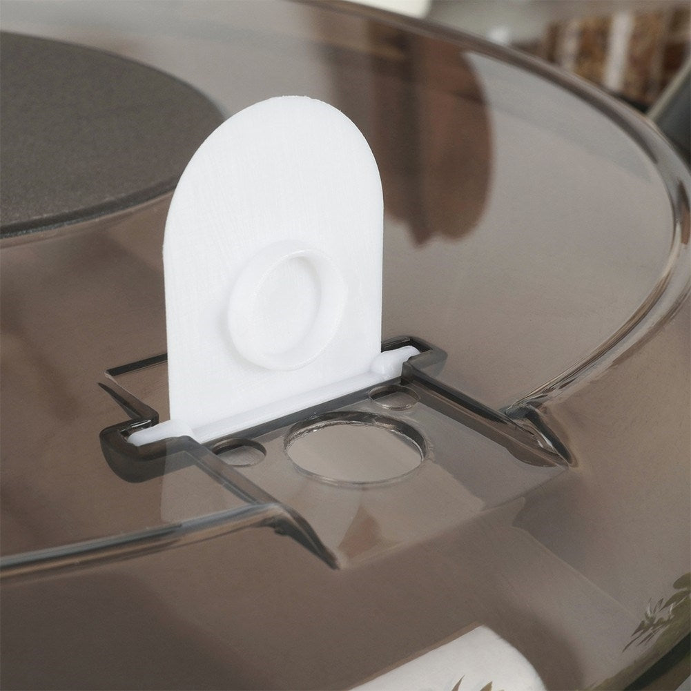 Primer plano de una tapa de plástico transparente con un filtro blanco y rectangular. La tapa tiene un marco negro y un agujero circular.