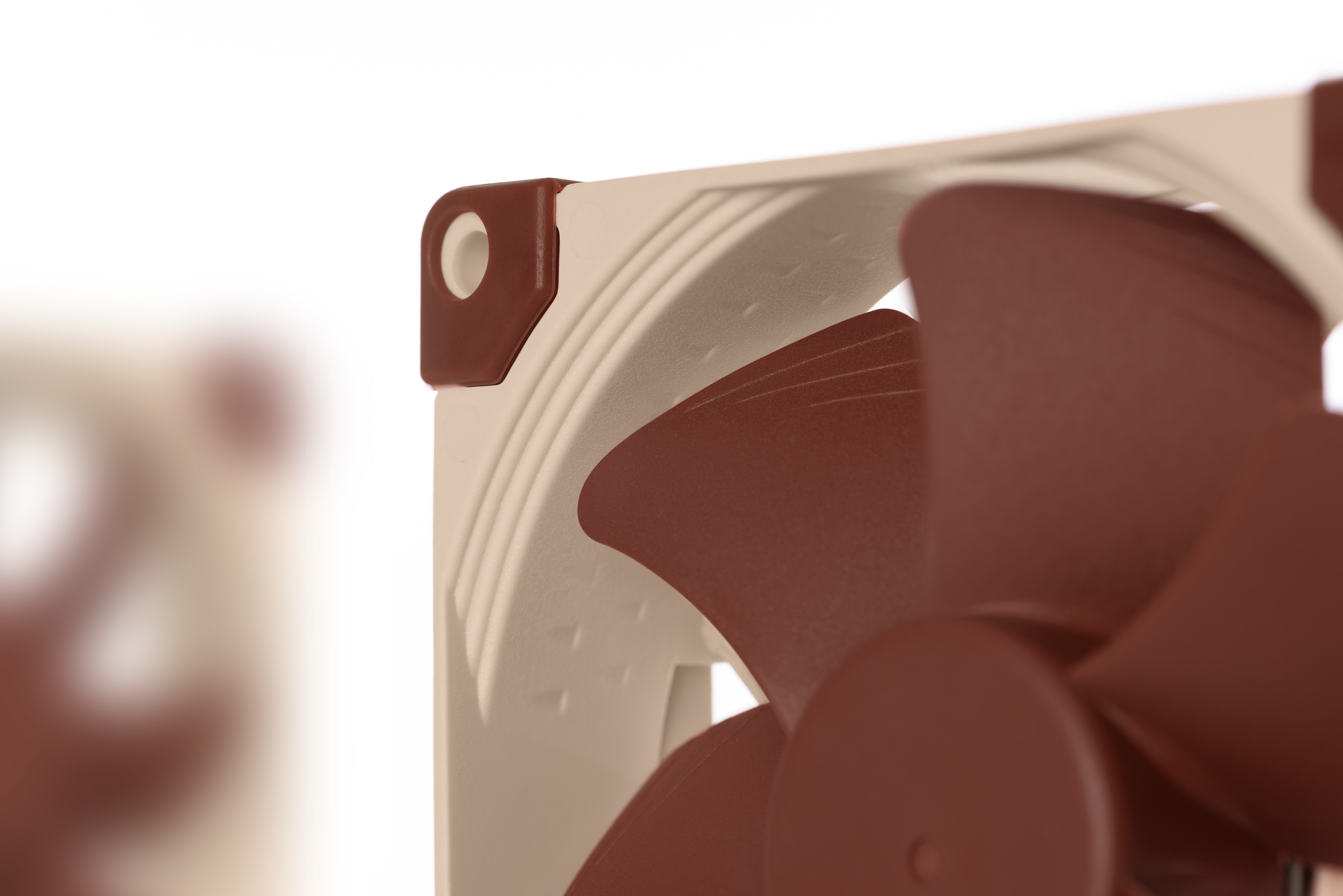 Primo piano di una ventola per computer con pale marroni e cornice beige, su sfondo bianco. L'attenzione è sui dettagli.