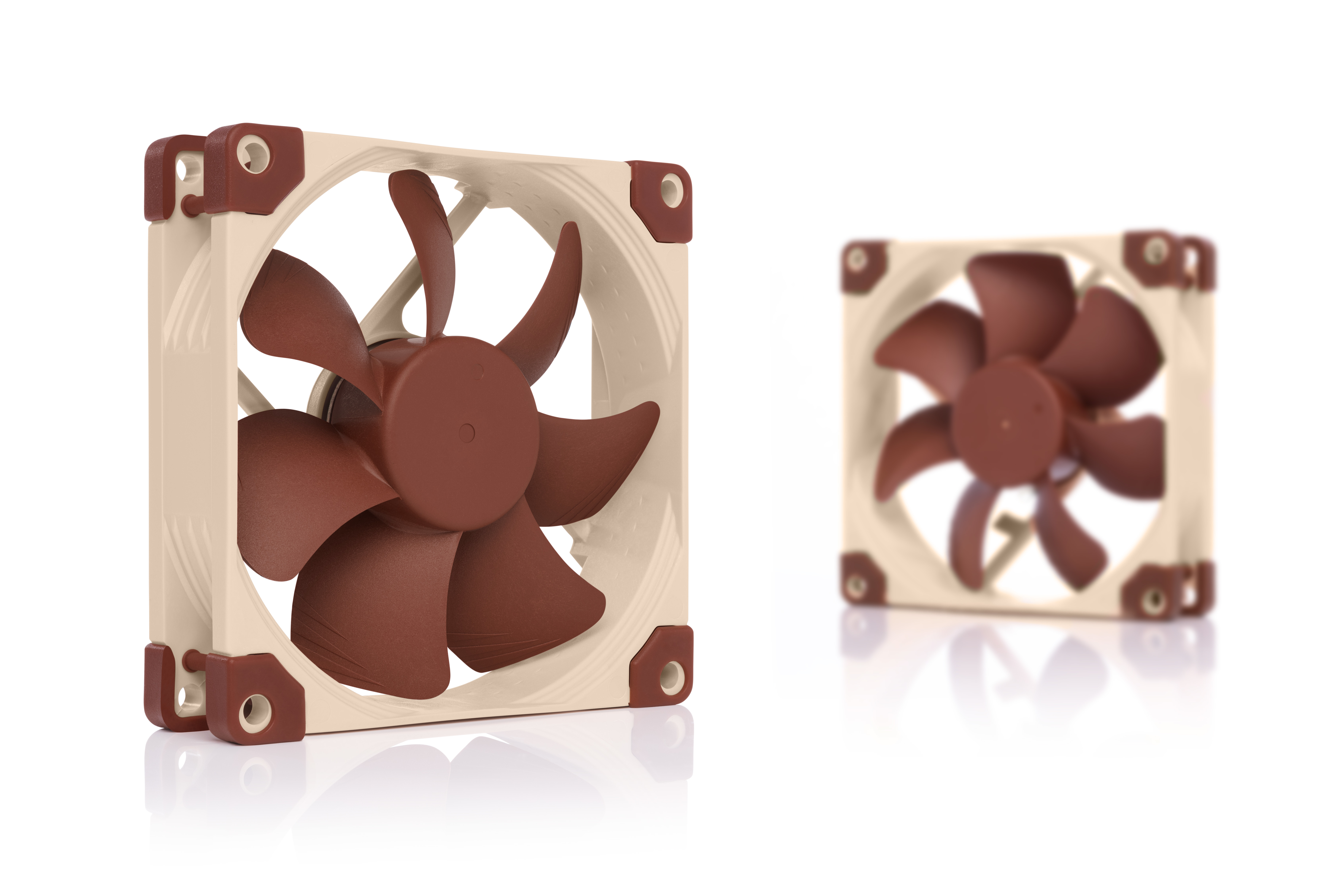 Due ventole per computer. Una a fuoco, l'altra sfocata. Hanno pale marroni e cornici beige su sfondo bianco.