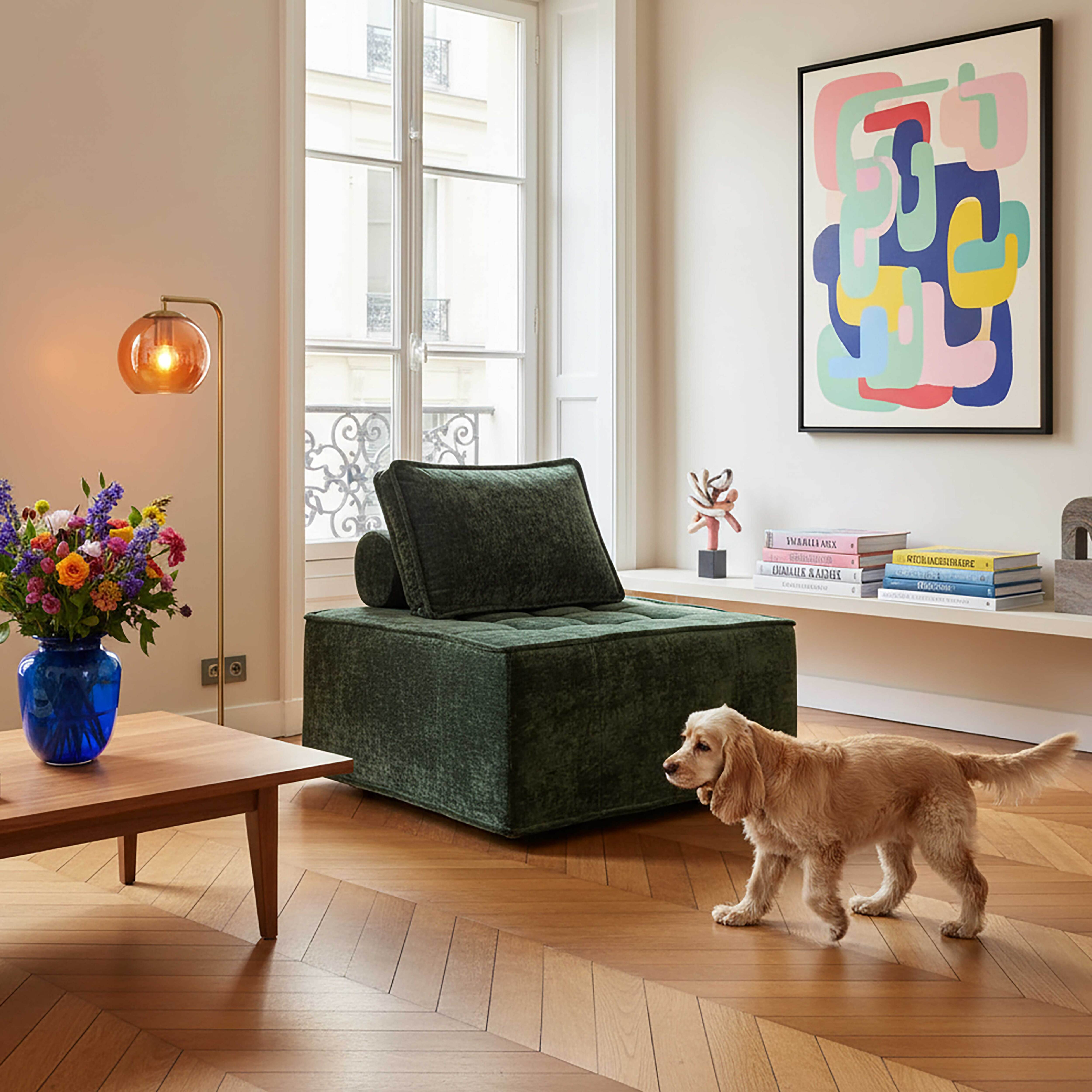 Ein Wohnzimmer mit grünem Sofa, Holztisch, blauer Vase mit Blumen, Hund und abstrakter Kunst.