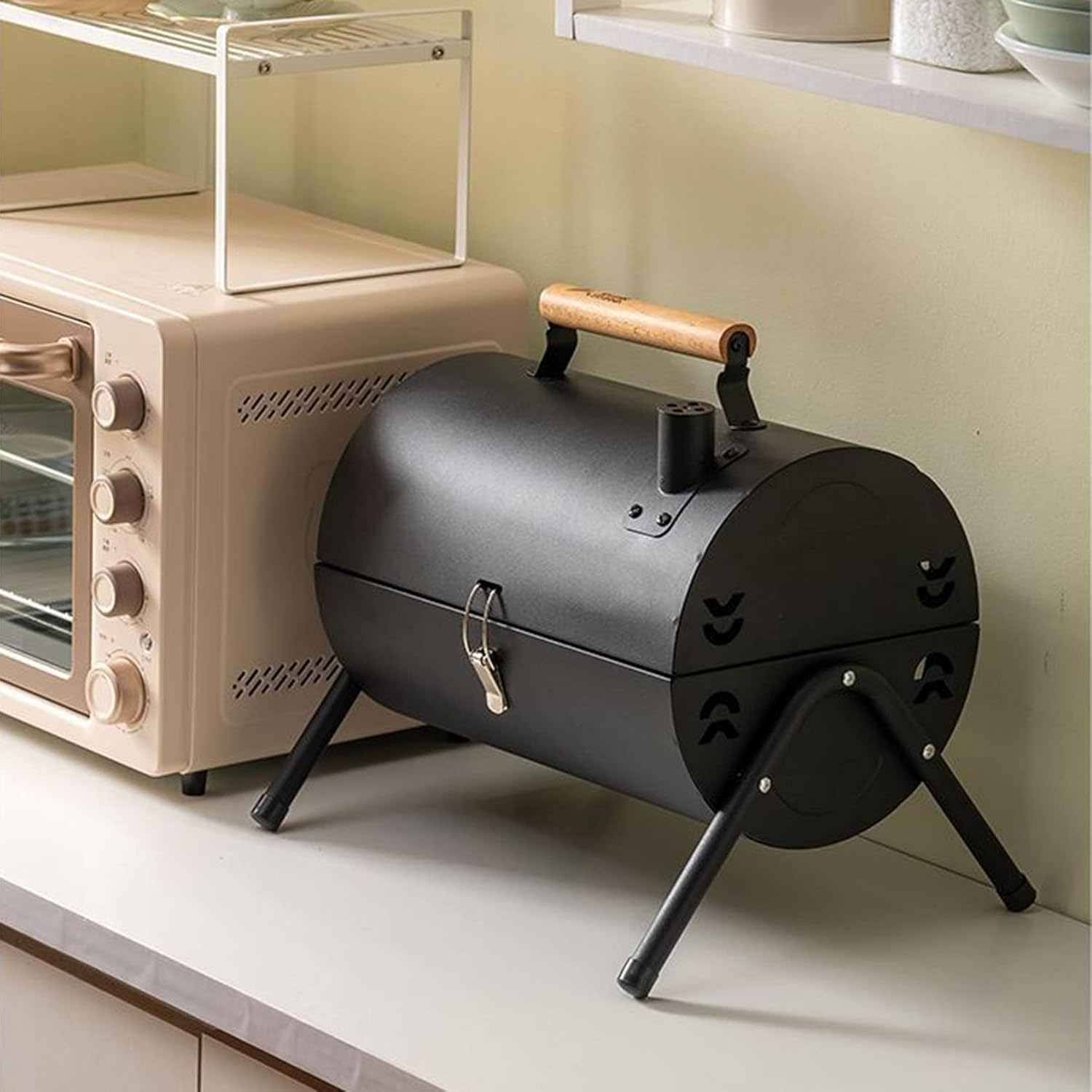 Ein schwarzer Fassgrill mit Holzgriff steht neben einem rosa Ofen. Über dem Ofen befindet sich ein weißes Regal.