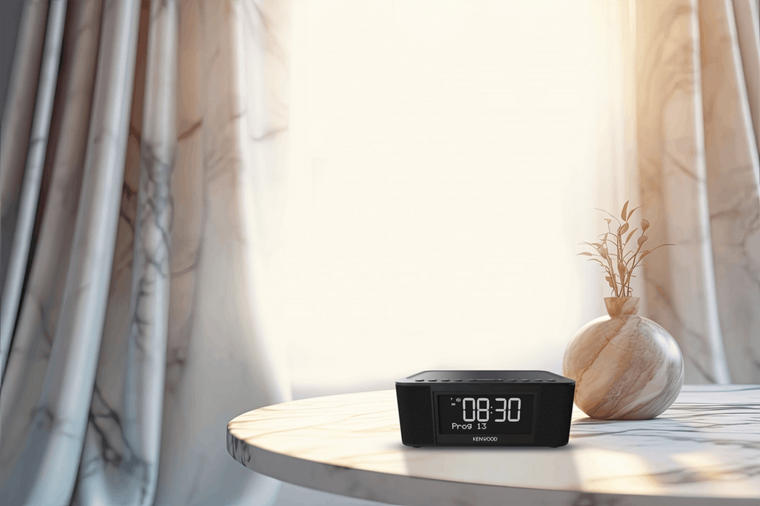 Czarny radiobudzik Kenwood wyświetla '08:30' na marmurowym stole. Obok wazon z roślinami, w tle zasłony.