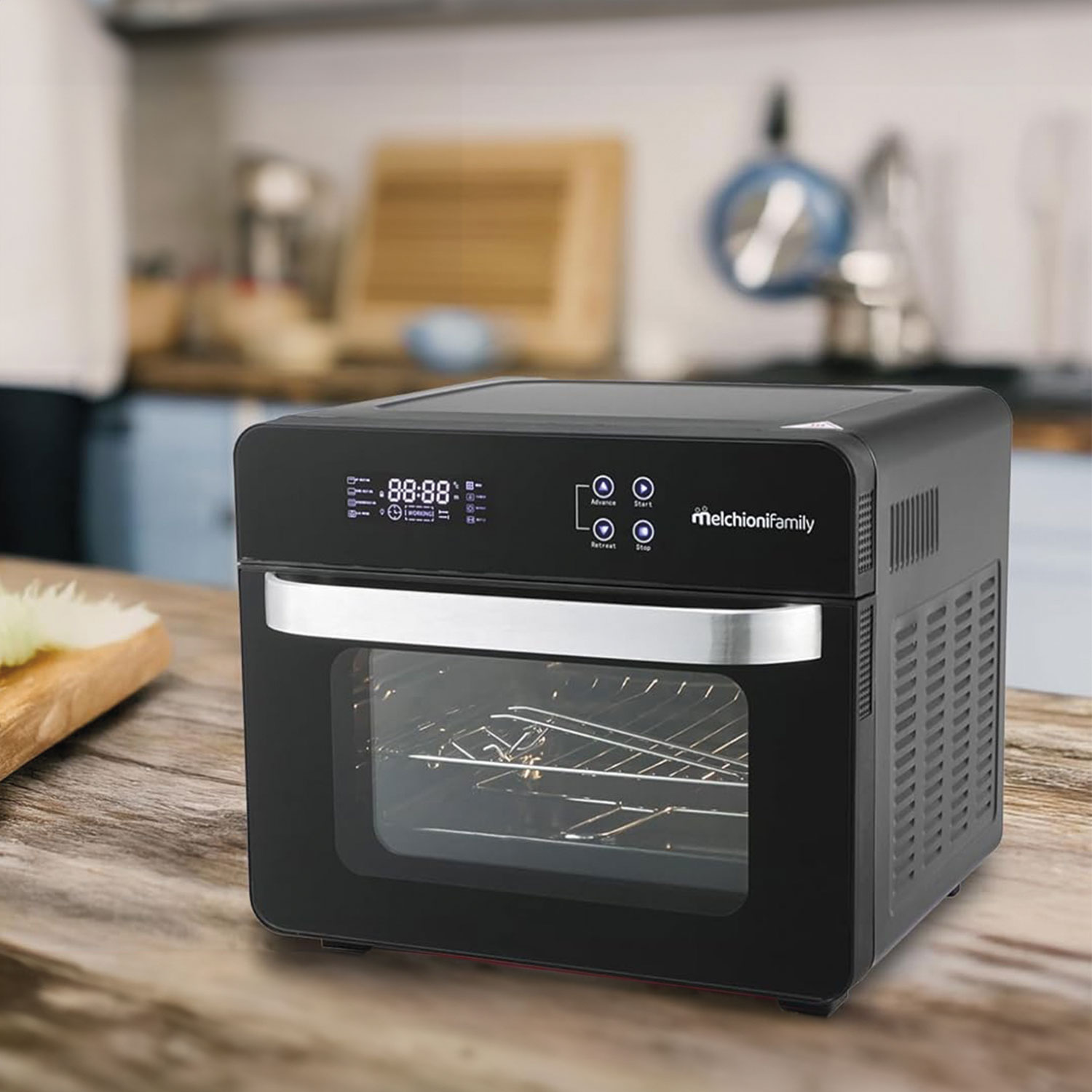 Un horno negro Melchionifamily sobre una superficie de madera. El horno tiene una pantalla digital y una puerta de vidrio, con una cocina al fondo.