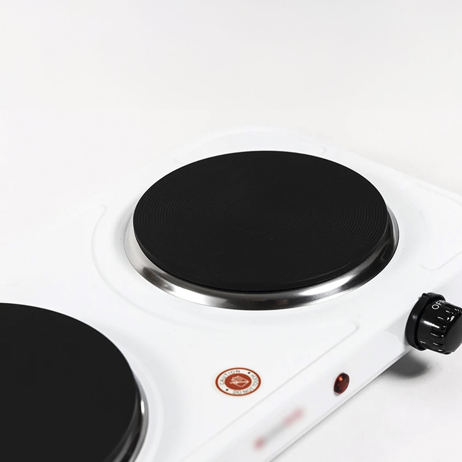 Biała przenośna kuchenka elektryczna z dwoma czarnymi płytami grzewczymi. Czarny guzik po prawej stronie mówi WYŁ. Świeci się czerwone światło.