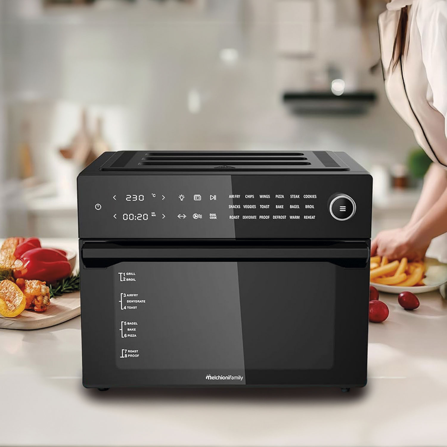 Czarny piekarnik z frytownicą MelchioniFamily stoi na blacie kuchennym. Jedzenie jest po lewej i prawej stronie. Osoba stoi w pobliżu piekarnika.