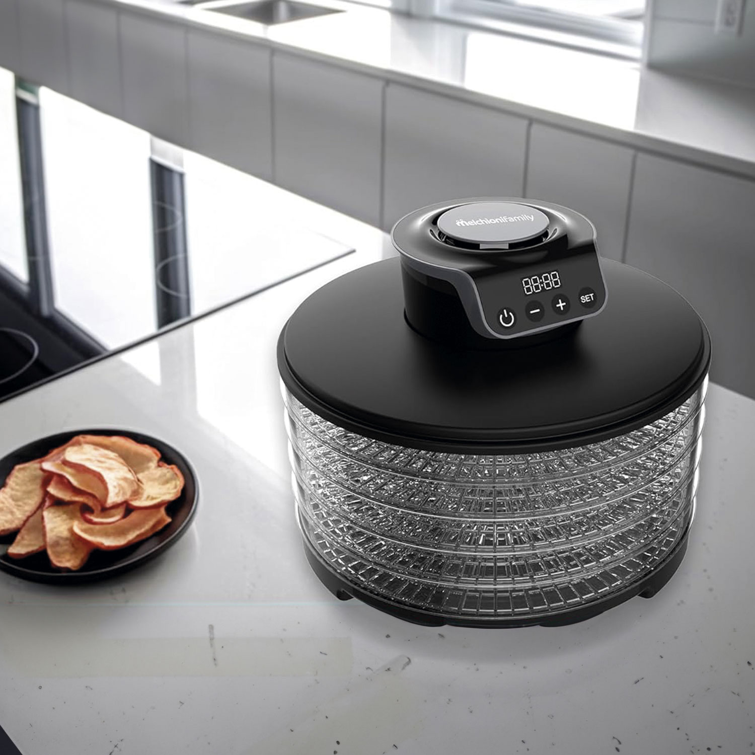 Un deshidratador de alimentos negro con pantalla digital sobre encimera. Rodajas de manzana deshidratada en plato cercano. Fondo de cocina.