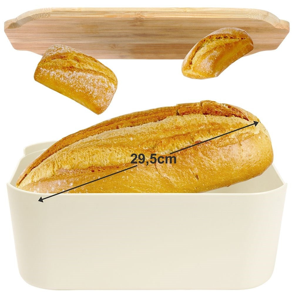 Una pagnotta in una scatola per il pane bianca, con due pani più piccoli e un tagliere di legno sopra. Il pane grande è lungo 29,5 cm.