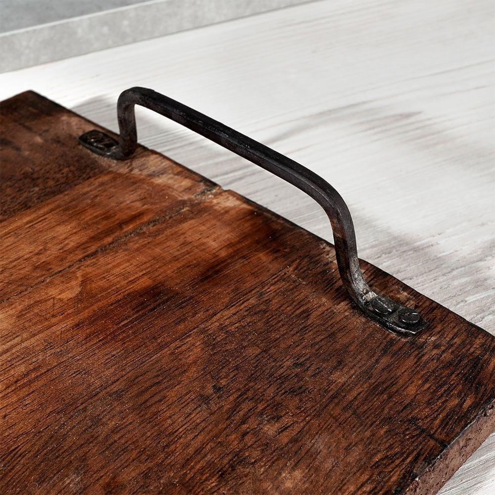 Un vassoio di legno con manico in metallo nero. Il vassoio è marrone e il manico è curvo.