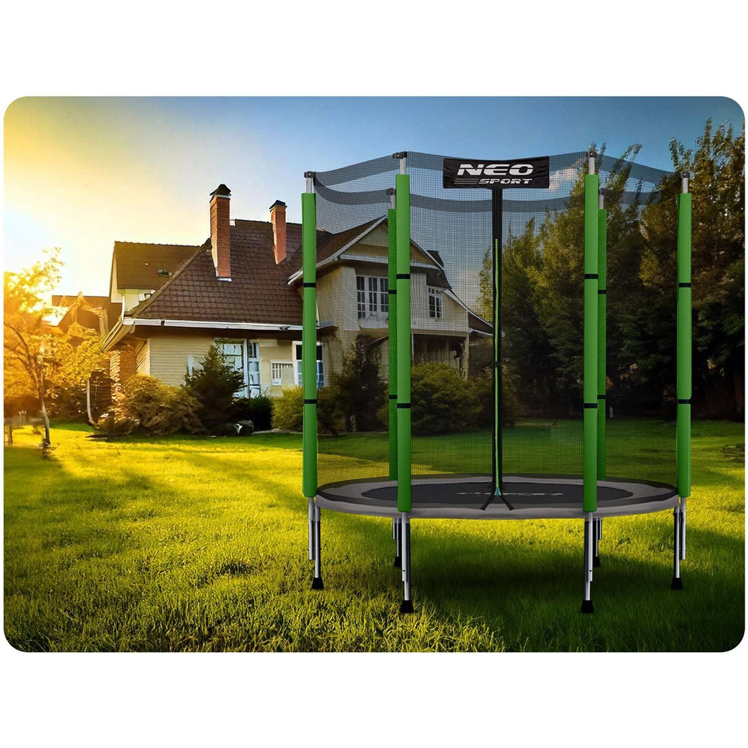 Un trampolín en un jardín. Marco verde, estera y red negras. Una casa al fondo y árboles. Día soleado, hierba verde.