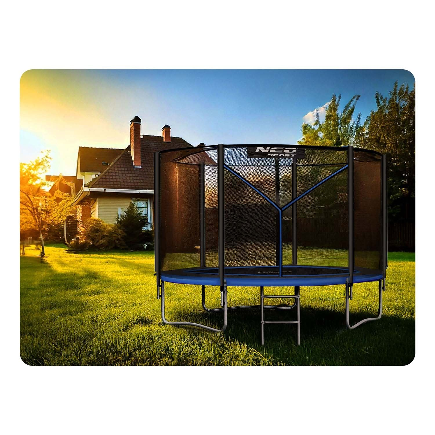 Un trampolín en un jardín con una casa al fondo. El trampolín es negro y azul. La hierba es verde.