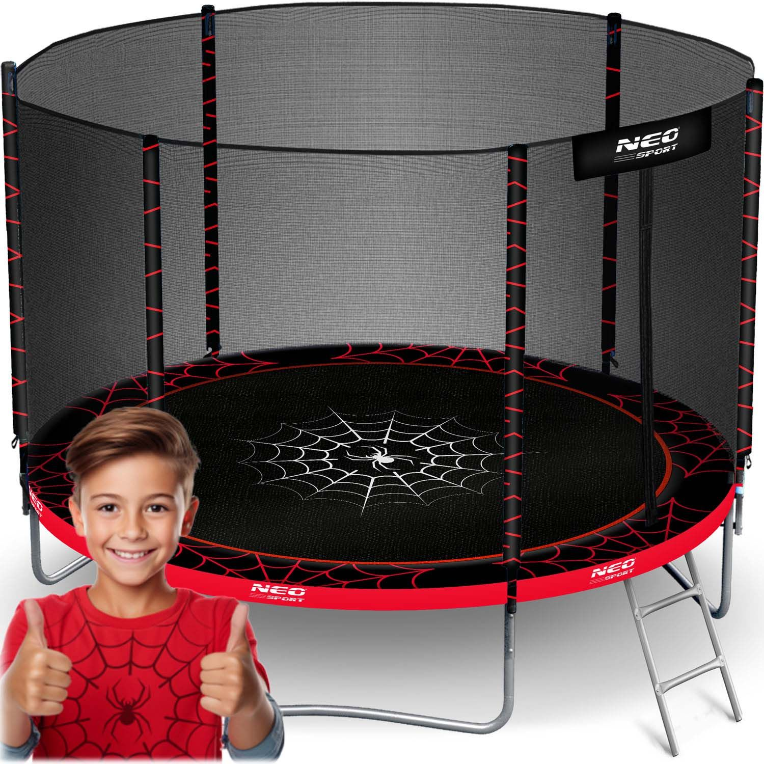 Un niño hace una señal de aprobación frente a un trampolín. El trampolín tiene un diseño de telaraña y una red de seguridad.