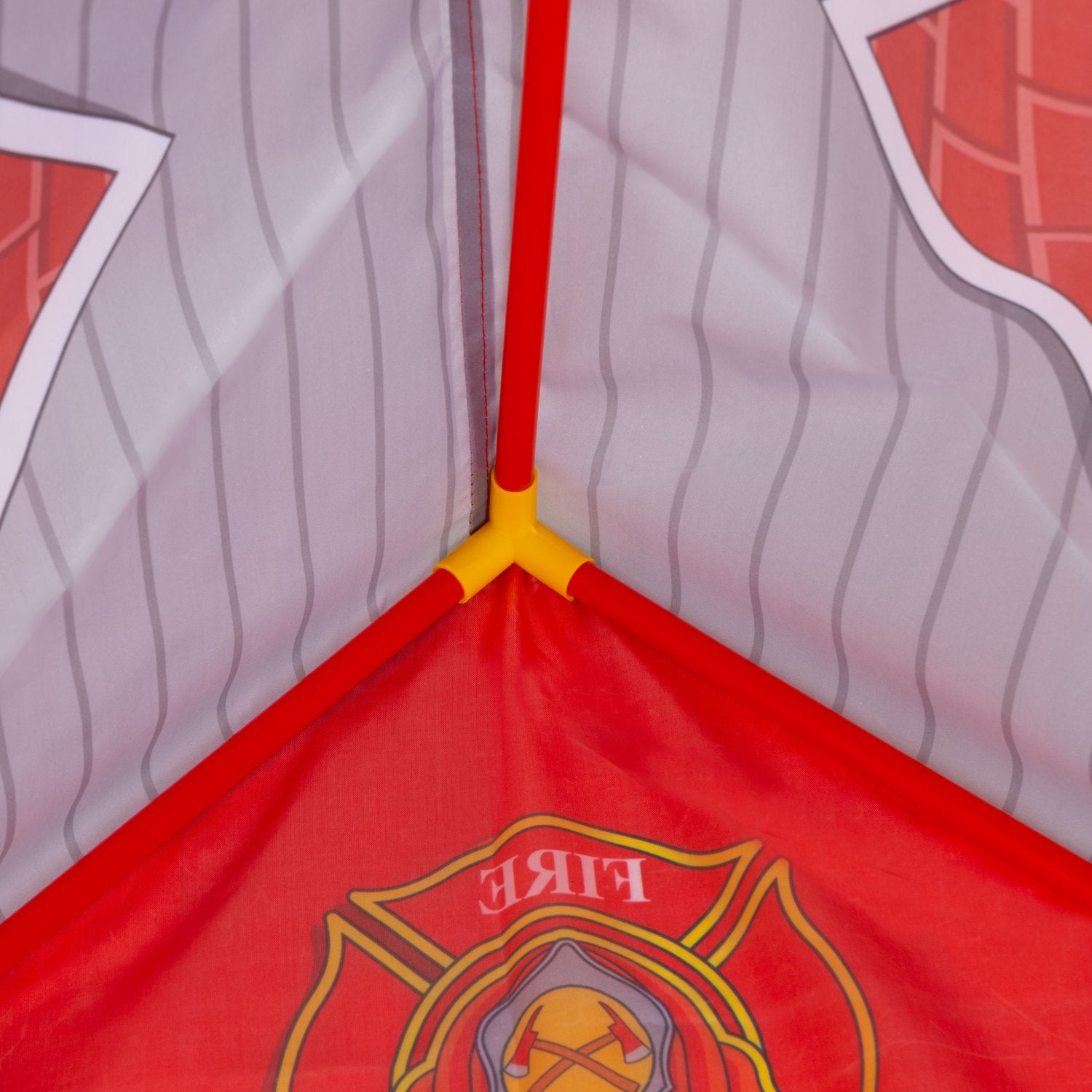 Interior de una tienda de campaña roja y blanca con el logo de bombero. Los postes rojos forman el marco, reuniéndose en las uniones amarillas. El fondo es rayado.