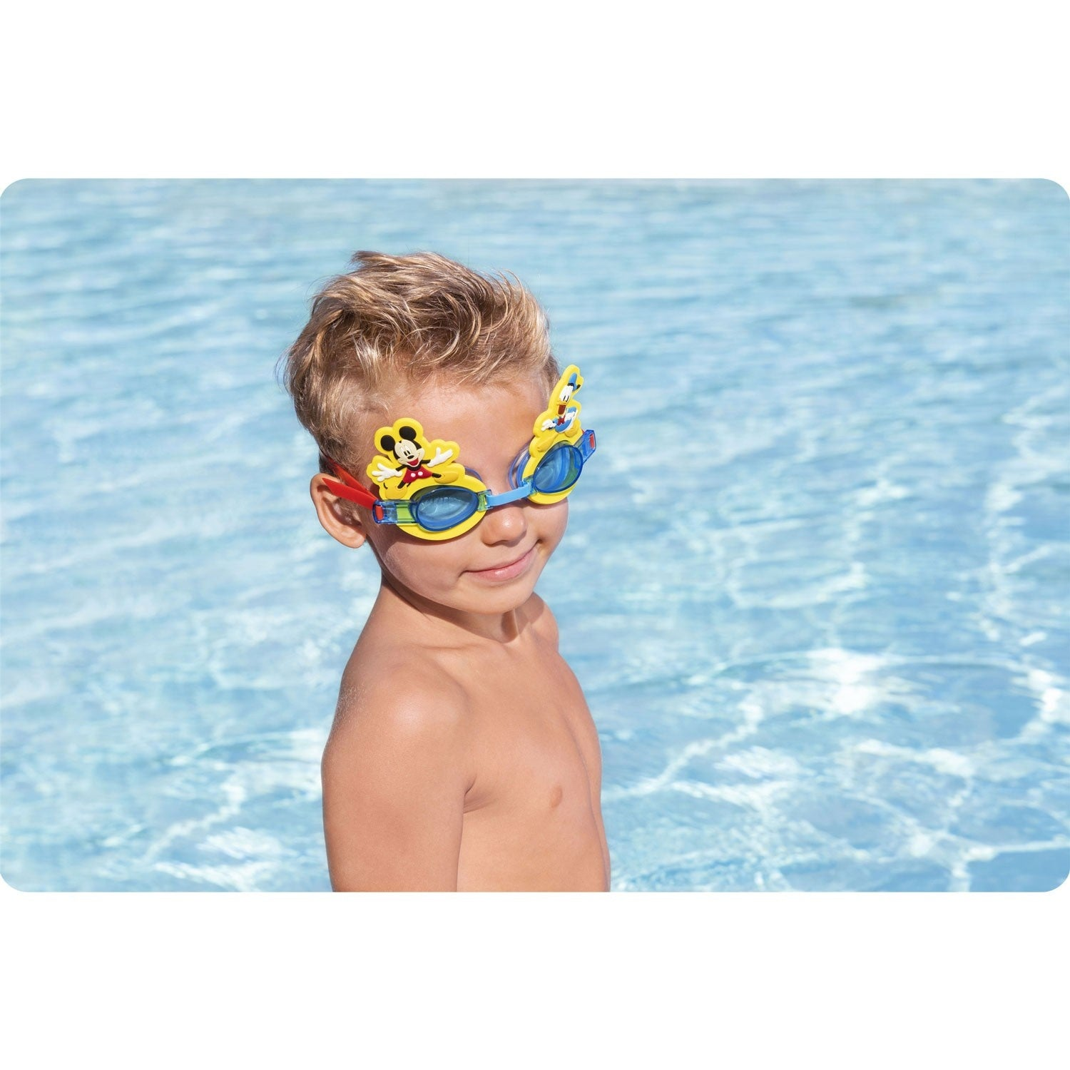 Un niño con gafas de natación de Mickey Mouse sonríe en una piscina. El fondo muestra agua con reflejos.