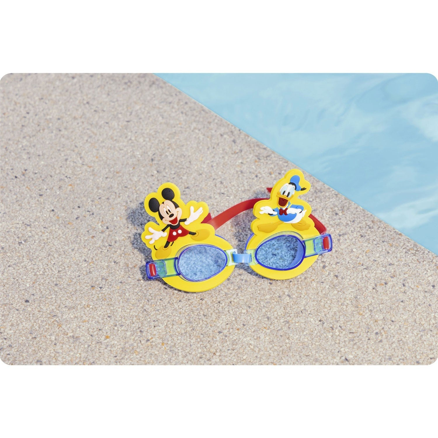 Gafas de natación amarillas de Mickey Mouse y Pato Donald sobre una superficie texturizada junto a una piscina azul.