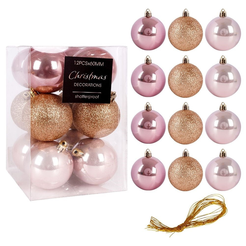 Adornos navideños en una caja transparente y organizados. Hay bolas rosas, doradas y doradas con purpurina. Una cuerda dorada en la parte inferior.