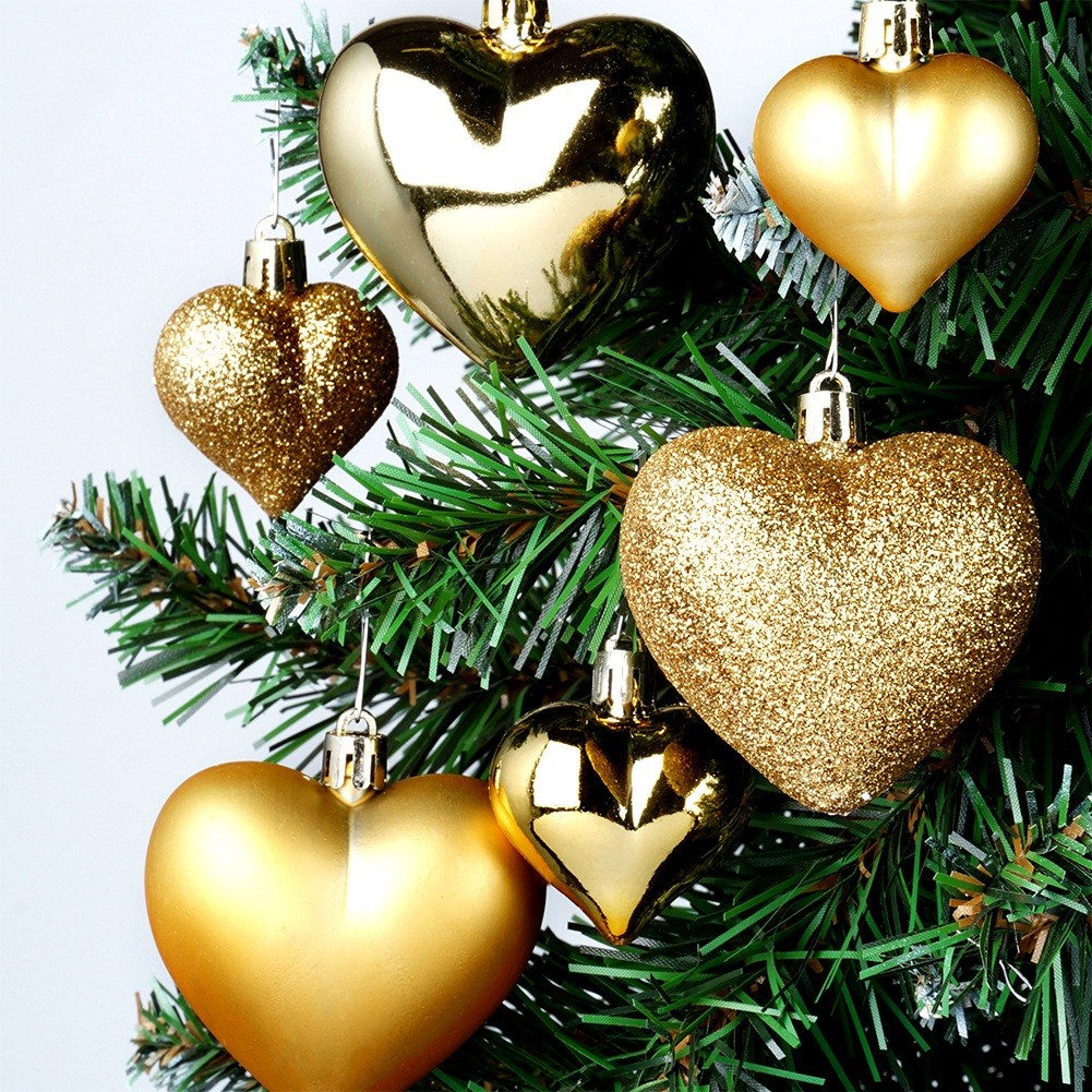 Primer plano de un árbol de Navidad con adornos dorados en forma de corazón. Algunos corazones son brillantes, otros lisos. Las agujas verdes son el fondo.