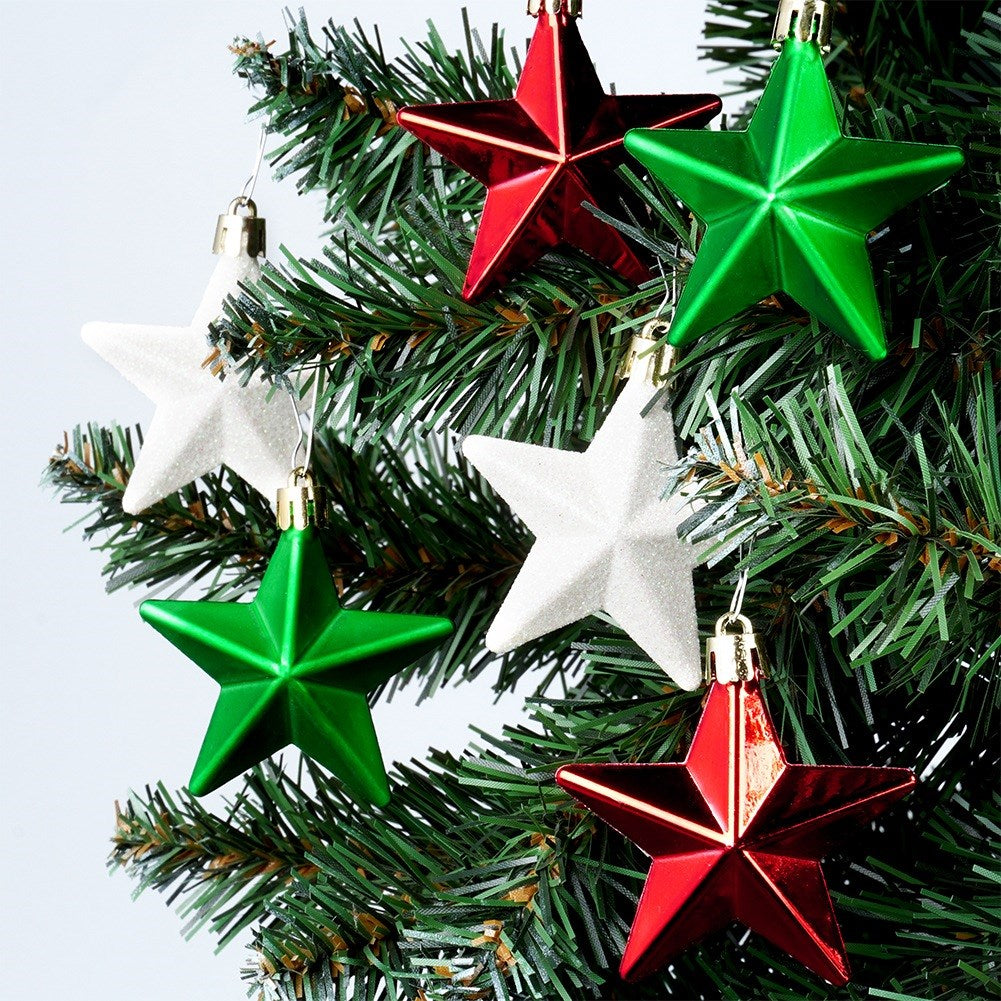 Primer plano de adornos navideños. Hay cinco adornos en forma de estrella de color blanco, rojo y verde en el árbol.