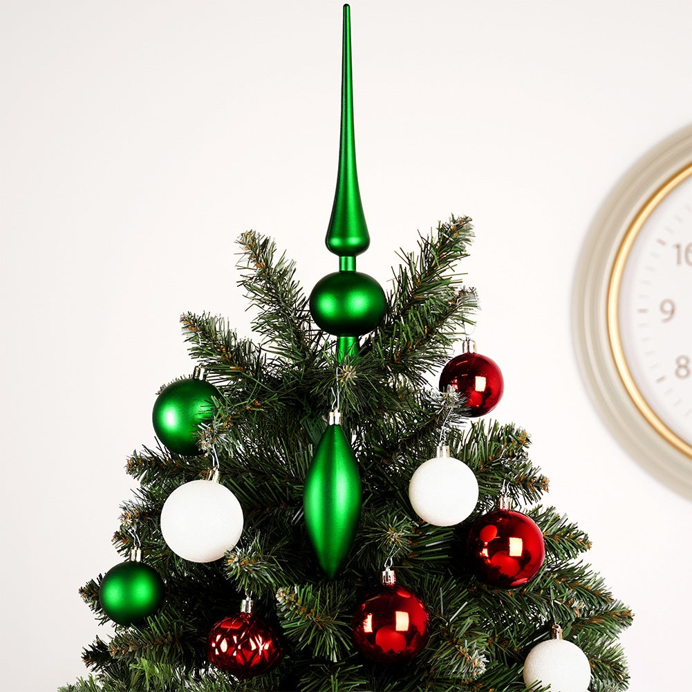 Un árbol de Navidad decorado con adornos verdes y rojos y un adorno verde en la parte superior. Un reloj es visible en el fondo.
