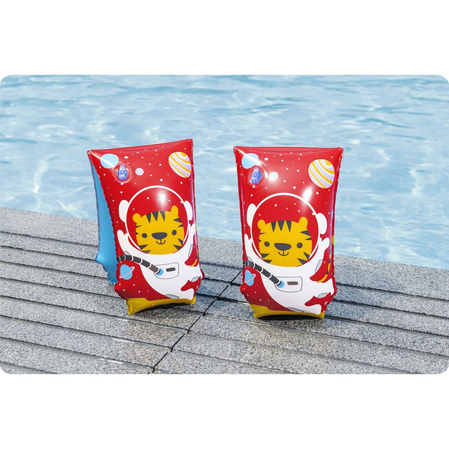 Dos flotadores de brazo rojos con diseño de tigre astronauta están sobre una plataforma de piscina. El fondo muestra una piscina azul clara.