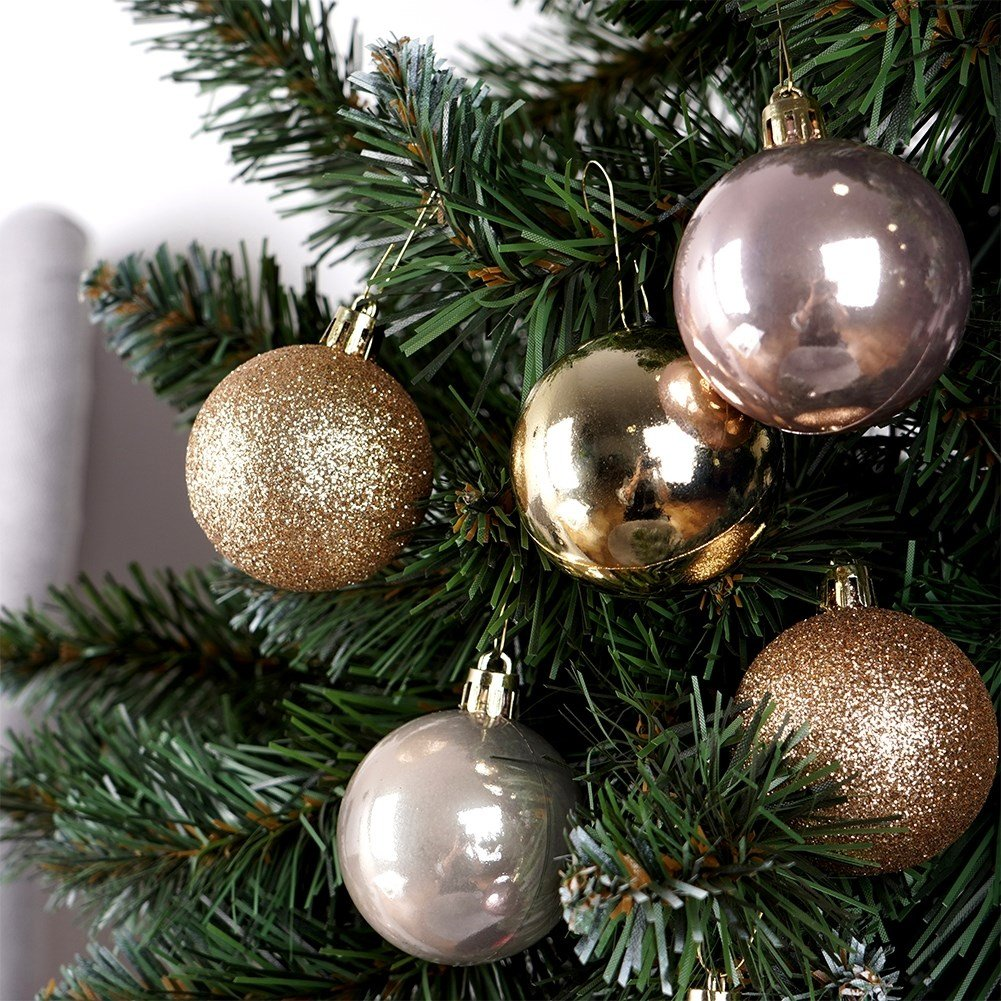 Primer plano de un árbol de Navidad con adornos. Bolas doradas, plateadas y oro rosa cuelgan de las ramas verdes.