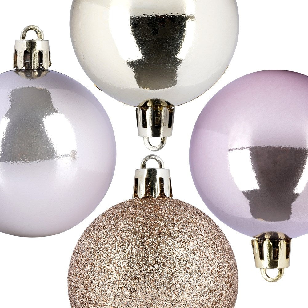 Cuatro adornos navideños: plateado, lavanda, rosa pálido y purpurina dorada. Tienen tapas metálicas y cuelgan sobre un fondo blanco.