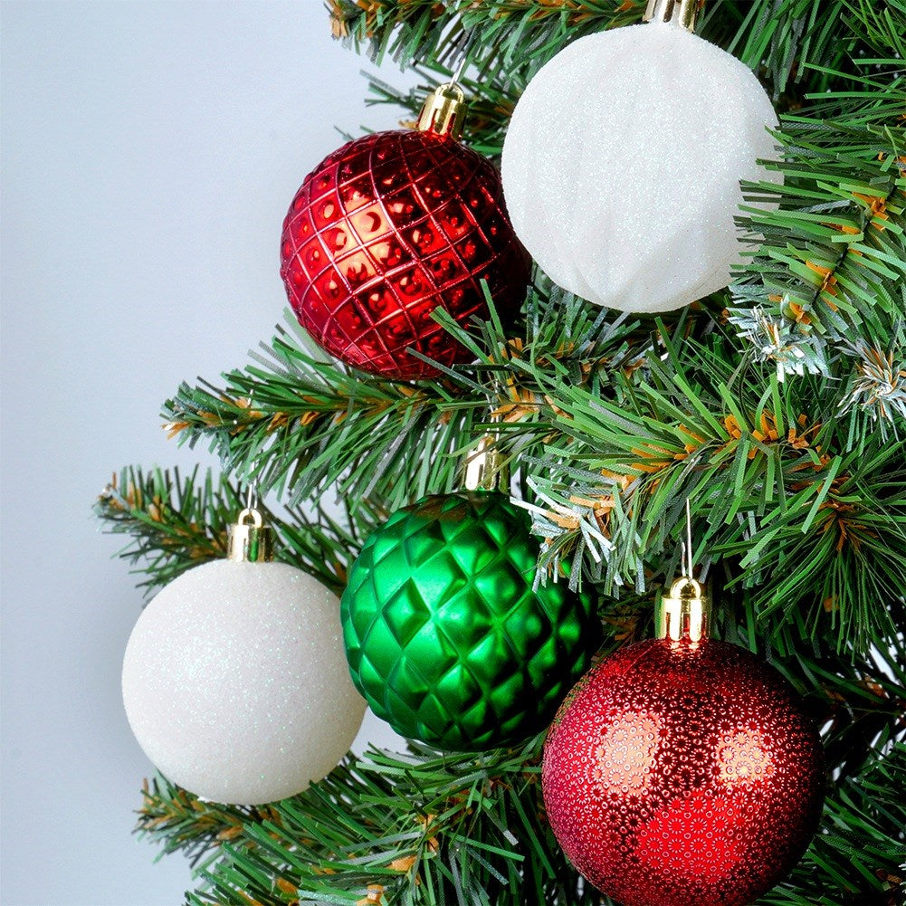 Árbol de Navidad con adornos rojos, verdes y blancos. Los adornos tienen varias texturas. El fondo es de color gris claro.
