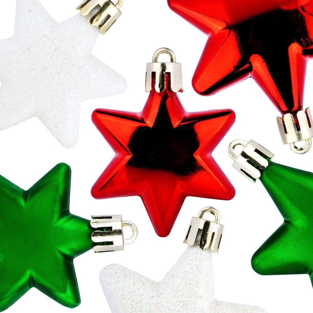 Primer plano de adornos de estrellas navideñas. Estrellas rojas, verdes y blancas con tapas plateadas esparcidas sobre fondo blanco.