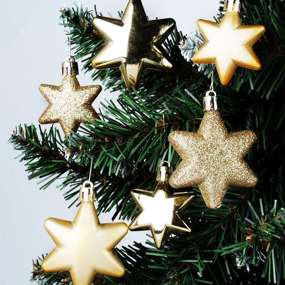 Primer plano de un árbol de Navidad con varios adornos de estrellas doradas. Las estrellas tienen diferentes texturas, algunas brillantes, otras con purpurina, todas doradas.