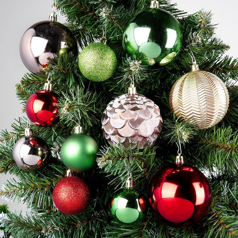 Un árbol de Navidad está adornado con varios adornos coloridos. Bolas rojas, verdes, doradas y plateadas brillantes cuelgan entre las agujas verdes.