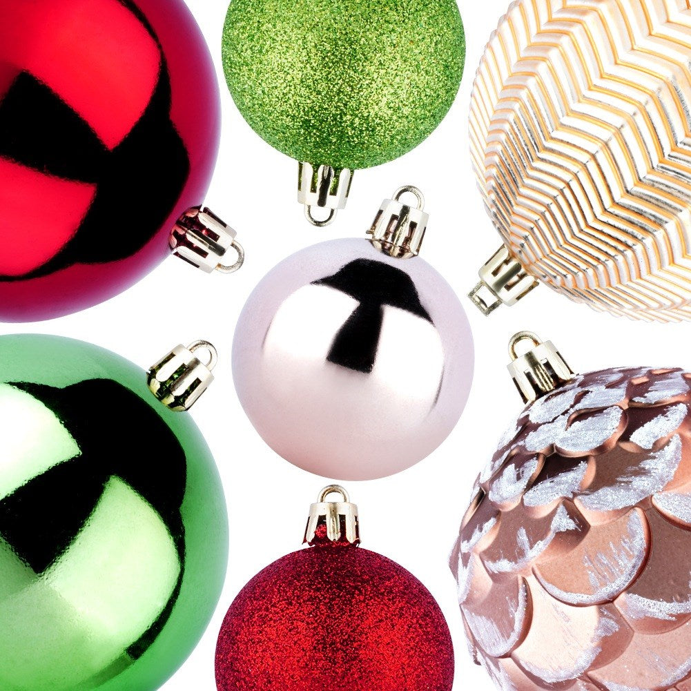Varios adornos navideños. Bolas rojas, verdes, plateadas y doradas, algunas brillantes o estampadas, sobre un fondo blanco.